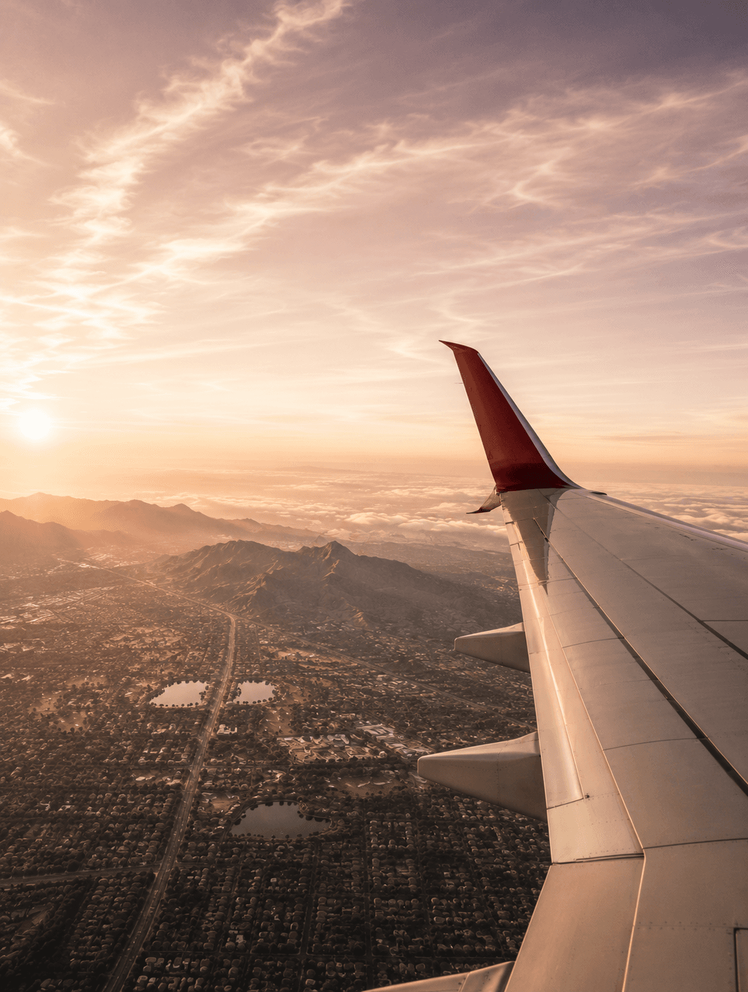 An airplane wing above Scottsdale at sunset.